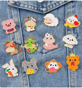 Detail of twelve cute zodiac enamel pins set displayed on denim fabric background