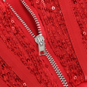 Détail macro de la fermeture éclair en métal et des paillettes rouges de la robe
