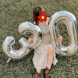 Large 40 inch silver number 30 foil balloons held outdoors on grass for birthday decor