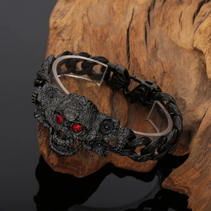 Detail of gothic black skull bracelet with red crystal eyes on a rustic wood background