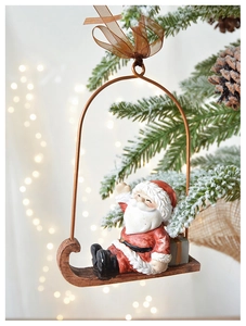 Detail of vintage Santa on a wooden sleigh hanging on a snowy Christmas tree branch