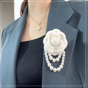 Elegant camellia flower brooch with pearl tassels on a dark suit blazer