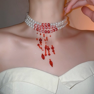 Close-up of elegant multi-layer pearl and red bead choker with a tassel pendant