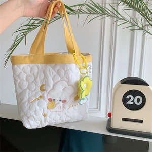 Close-up of white quilted tote bag with yellow straps and cute flower charm detail