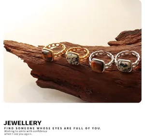 Detail of vintage tiger eye stone rings with chain-style adjustable bands on wood