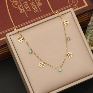 Detail of gold-plated tree of life charms and turquoise beads on a stainless steel necklace