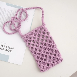 Handmade purple macrame knit phone bag with cross-body strap on a minimalist magazine
