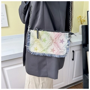 Detail of star pattern and fringe trim on a colorful checkered denim crossbody bag