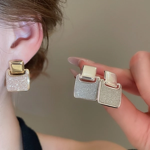 Detailed close-up of 18k gold plated square glitter earrings worn by a model