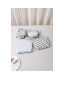Vue détaillée des trousses de toilette rayées avec nœuds brodés et fermeture éclair