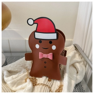 Gingerbread man crossbody bag with a red Santa hat and gold chain on a warm knit background