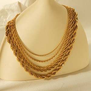 Detail of layered gold rope chains on a beige bust showing textured metallic finish