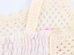 Close-up of cream crochet knit pattern with pleated fabric detail on a crop top