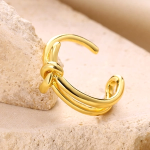 Close-up of gold-plated knotted triple-strand ring on a natural stone display