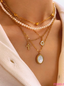 Detail of layered gold-plated necklaces with pearls, heart charms, and shell pendant