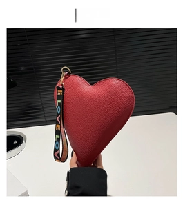 Détail du sac rouge en forme de cœur avec texture litchi et dragonne LOVE colorée