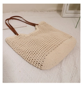 Detail of hollow-out mesh woven tote with cream cotton thread and brown leather straps