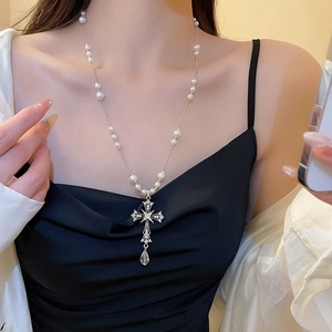 Dettaglio collana di perle vintage con ciondolo a croce di diamanti e gemma a goccia