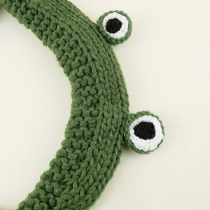 Close-up of handmade green knitted frog headband showing soft yarn texture and detail