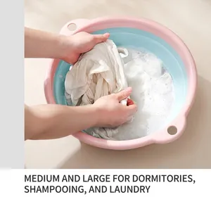 Lavage de vêtements à la main avec mousse dans une bassine pliable rose et bleue
