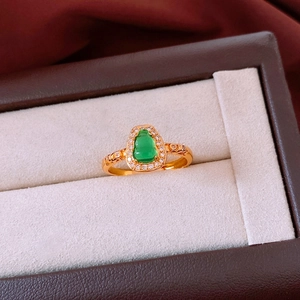 Detailed close-up of a vintage gold ring with a green gourd gemstone in a jewelry box