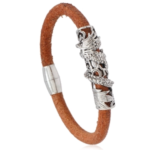 Detail of brown braided leather bracelet with intricately engraved silver dragon metal charm