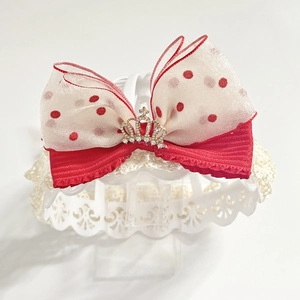 Close-up of red and white polka dot lace headband with a golden crown rhinestone