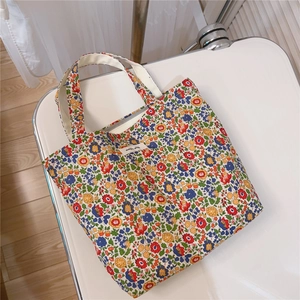 Detailed top view of a colorful floral cotton canvas tote bag with a zipper and branded label