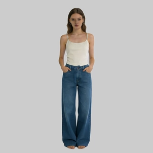 Vista frontale di jeans a gamba larga a vita alta blu scuro con canotta bianca per donna