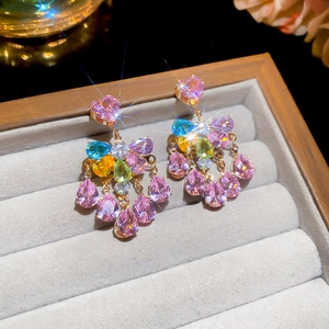 Macro view of gold-tone earrings with pink, yellow, and blue heart-shaped cubic zirconia