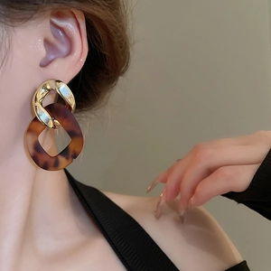 Close-up of leopard resin earrings with gold links worn by a model for a stylish look