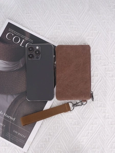 Brown washed canvas coin purse with wrist strap next to smartphone for size reference