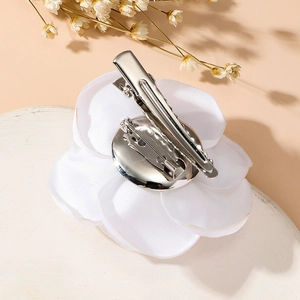 Detail view of the white fabric rose brooch showing the functional metal dual-use clip back