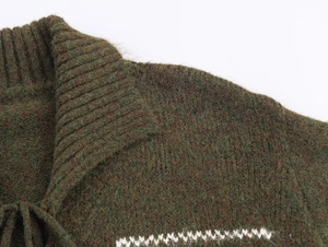 Detailed view of dark green knit cardigan featuring textured fabric and white wave patterns