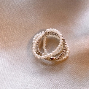 Detailed macro shot of elegant multi-layered pearl ring on champagne silk fabric