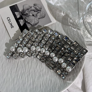 Elegant silver hair clips set with crystals and pearls displayed on a white plate