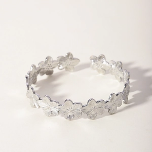 Detailed macro view of silver floral pattern stainless steel open cuff bracelet