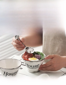 Detail of white ceramic bowl with silver trim and stainless steel spoon with bear handle