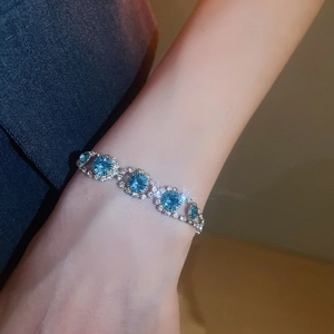 Close-up of a silver bracelet with large blue stones and zircon accents on a wrist