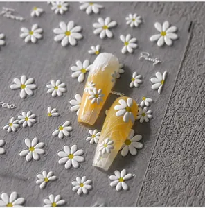 Detailed macro view of 3D embossed white daisy nail stickers on long yellow nails