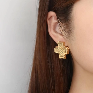 Women's 18K gold plated stainless steel textured cross earrings on a female model