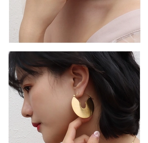 Macro detail of gold brushed titanium round earrings featuring an elegant metal texture