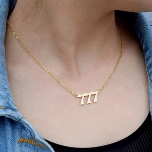 Detail of gold-plated angel number 777 pendant necklace on a stylish model
