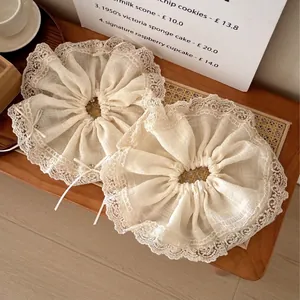 Cream lace bow scrunchies with faux pearls on a rustic tray for elegant hair styling