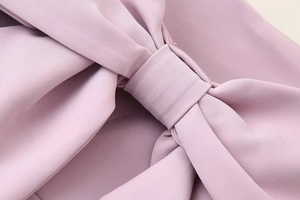 Detailed view of a sweet pink dress featuring a decorative bow knot and smooth fabric