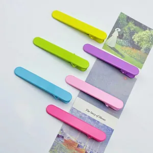 Set of six macaron-colored 6cm matte alligator hair clips arranged on a white desk