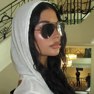 Classic gold metal aviator sunglasses with black lenses shown on a female model