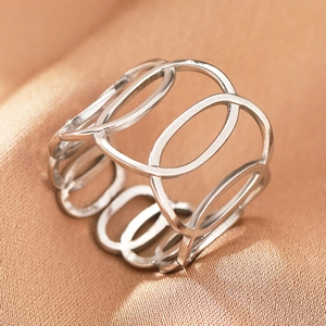 Close-up of bohemian hollow geometric silver stainless steel ring on gold satin fabric