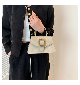 Detail of beige vintage crossbody bag with golden braided buckle on a model side view