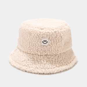 Close-up of cream white plush bucket hat with a minimalist black smiley face patch